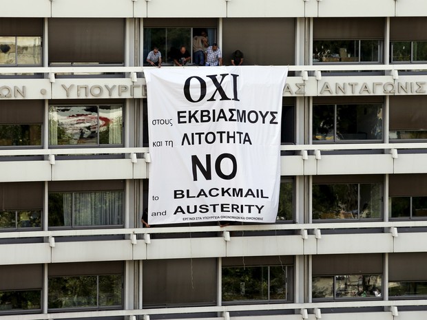 Funcionários do Ministério das Finanças e da Economia Nacional da Grécia colocam uma bandeira na varanda do Ministério em Atenas com a mensagem 'Não à chantagem e à austeridade'. O país não pagou uma parcela da dívida de € 1,6 bilhão com o FMI (Foto: Jean-Paul Pelissier/Reuters)