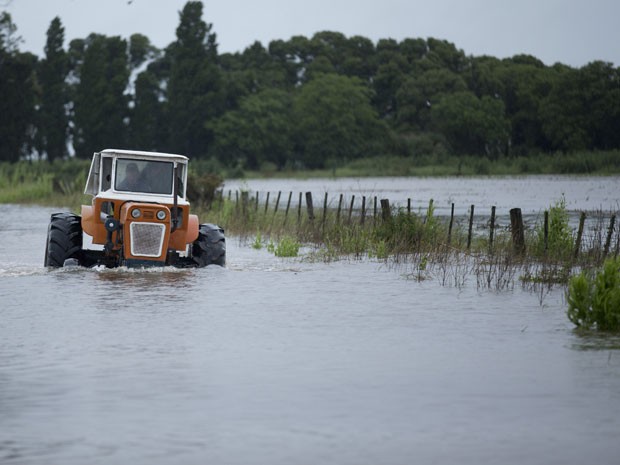 Homem dirige um trator em estrada alagada perto de Carmen de Areco, na Argentina, na segunda-feira (3) (Foto: AP Photo/Natacha Pisarenko)