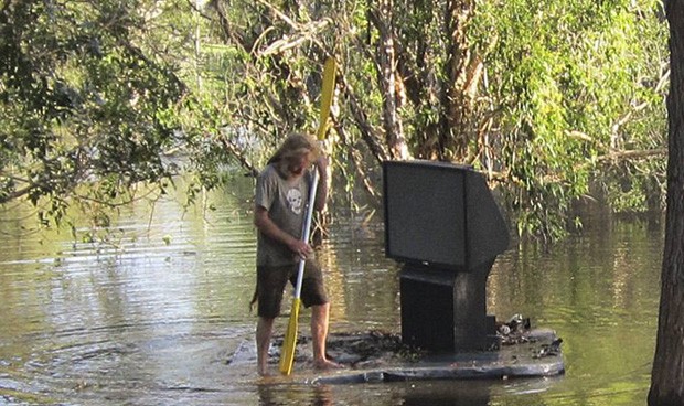 Em Cornubia, na Austrália, um homem foi flagrado transportando uma TV numa espécie de jangada, devido às enchentes que atingiram a região  (Foto: Stringer/Reuters)