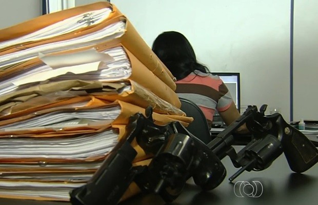 Arquivos de homicídios e armas apreendidas com suspeitos, em Goiânia (Foto: Reprodução/TV Anhanguera)