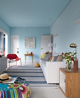 A parede na cor azul destaca o grafismo do adesivo branco, no projeto de Andrea Murao. O resultado parece papel de parede