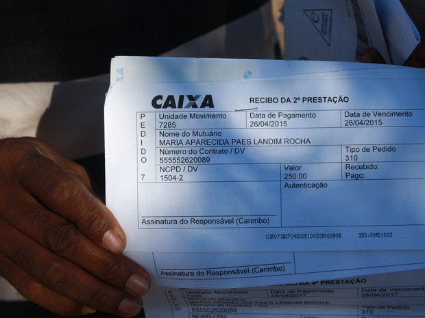 Morador mostra comprovantes de pagamento no nome da esposa (Foto: Gustavo Almeida/G1)
