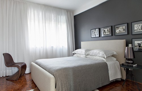 Simples, o quarto desenhado pelos arquitetos Marco Donini e Francisco Zelesnikar, do escritório Arqdonini, tem parede cinza e quadrinhos com fotos em preto e branco
