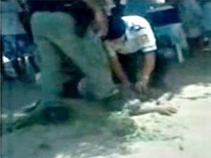 Policiais prendem a cabeça da vítima contra a areia no chão (Foto: Reprodução)