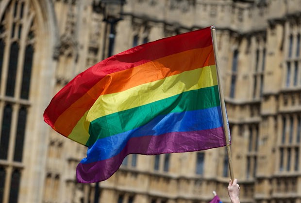 Bandeira gay tremula em frente ao prédio do Parlamento, em Londres, durante manifestação nesta segunda-feira (17) (Foto: Andrew Cowie/AFP)