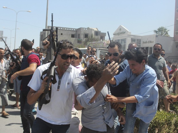 Policiais escoltam um homem suspeito de estar envolvido no atentado a um hotel em Sousse, na Tunísia. Pelo menos 27 pessoas , incluindo turistas estrangeiros, foram mortos quando pelo menos um atirador abriu fogo no hotel (Foto: Amine Ben Aziza/Reuters)
