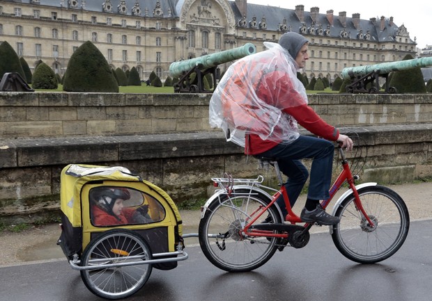 Menino observa paisagem enquanto é levado por ciclista em carruagem minúscula (Foto: Jacques Demarthon/AFP) Menino observa paisagem enquanto é levado por ciclista em carruagem minúscula (Foto: Jacques Demarthon/AFP)
