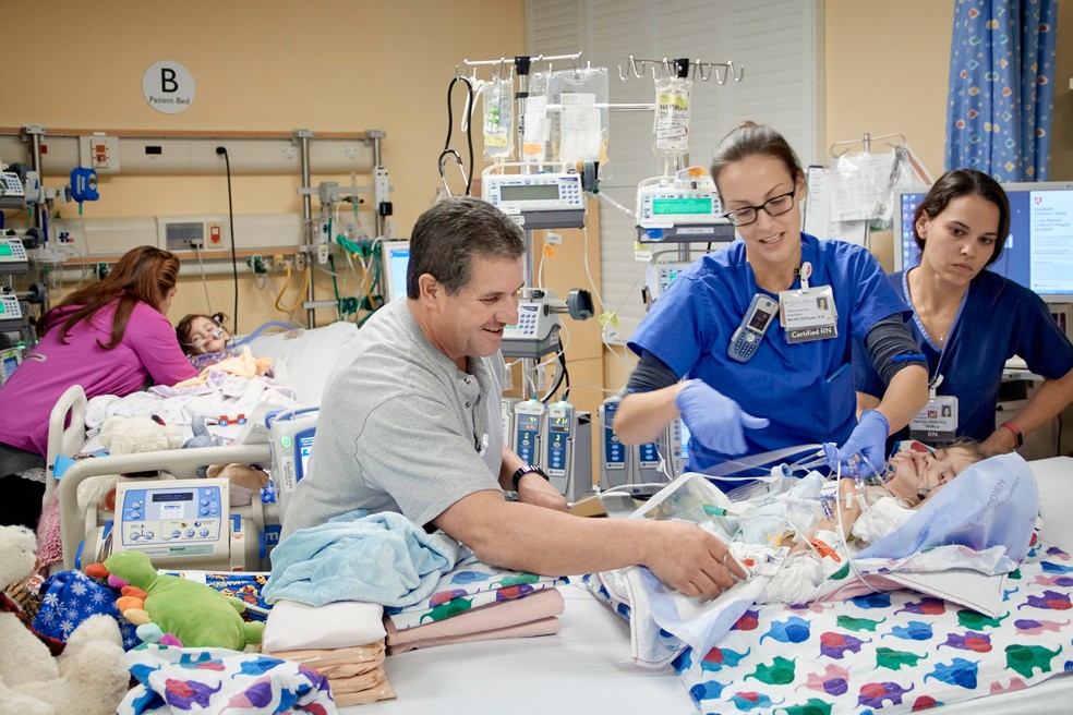 Arturo Sandoval, pai das gêmeas, ajuda a levar Erika para a cama de Eva ao lado da equipe da UTI pediátrica: siamesas foram separadas com sucesso  (Foto: Lucile Packard Children's Hospital Stanford via AP)