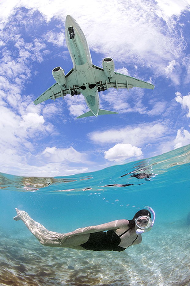 Foto de Daniel Botelho mostra mulher mergulhando em St. Maarten, no Caribe, enquanto avião sobrevoa a ilha (Foto: Daniel Botelho/Divulgação)