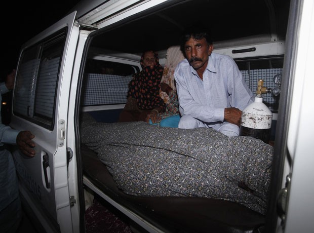 Mohammad Iqbal acompanha o corpo da mulher no necrotério, após ela ser apedrejada por membros da família (Foto: Mohsin Raza/Reuters)