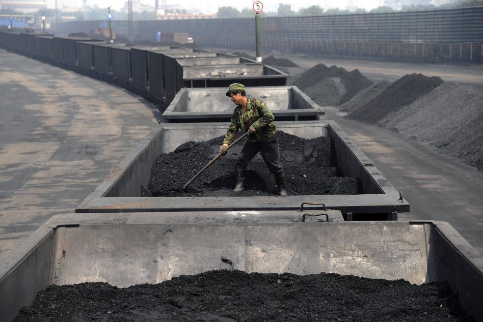 Trabalhador em carga de carvão transportada por trem na região de Shanxi, na China (Foto: Arquivo/AP)