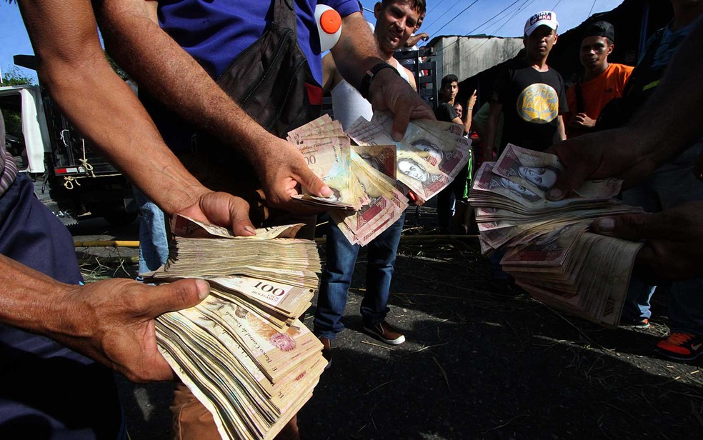 Venezuelanos mostram notas de 100 bolívares durante protesto (Foto: George Castellanos / AFP Photo)