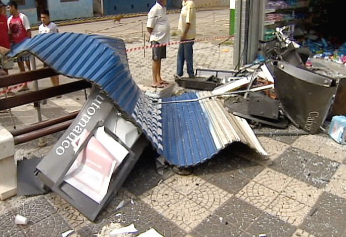 Porta da farmácia foi arremessada para a praça no centro de Jambeiro. (Foto: Reprodução/TV Vanguarda)