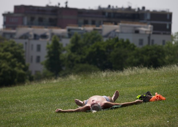 Homem toma sol em parque na região central de Londres (Foto: Andrew Cowie/AFP)