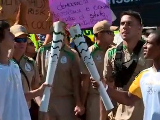 Manifestantes contra e a favor do impeachment se aproximam de condutores da tocha olímpica em Brasília (Foto: TV Globo/Reprodução) Manifestantes contra e a favor do impeachment se aproximam de condutores da tocha olímpica em Brasília (Foto: TV Globo/Reprodução)