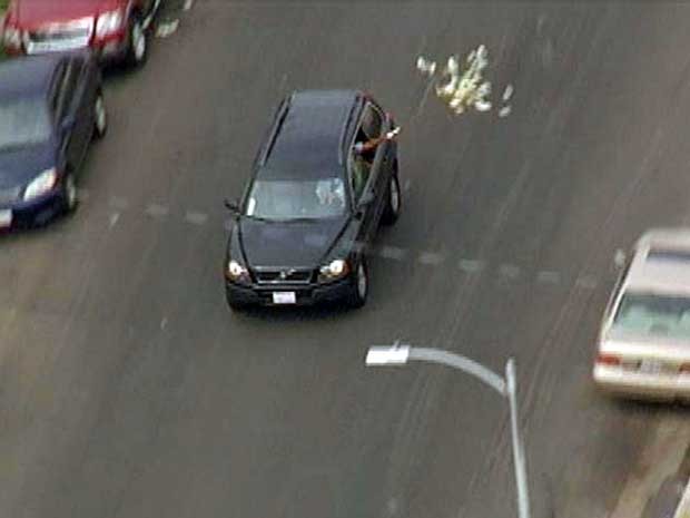 Imagem fornecida pele “KNBC TV” mostra momento em que assaltantes jogam dinheiro pela janela de um veículo, durante fuga após roubo a banco em Santa Clarita, na Califórnia. (Foto: KNBC TV / AP Photo)