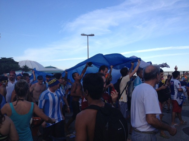 Argentinos cantam e dança depois da vitória debaixo de bandeirão em Copacabana (Foto: Alba Valéria Mendonça/ G1)