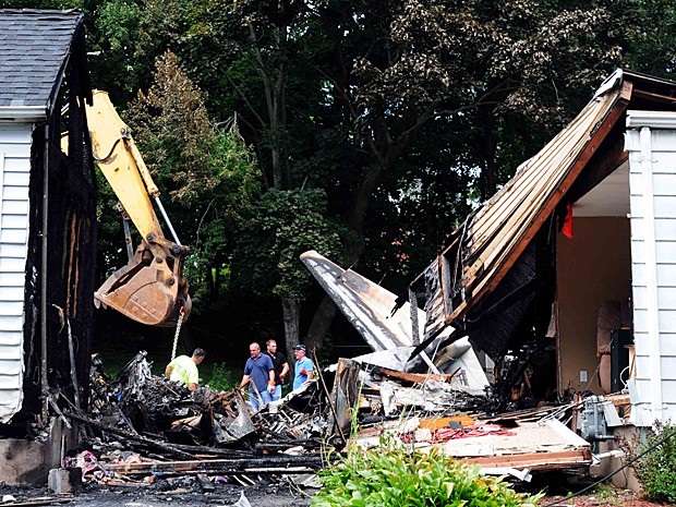 Oficiais inspecionam neste sábado (10) os destroços após queda de avião sobre duas casas em Connecticut (Foto: The New Haven Register, Peter Hvizdak/AP)