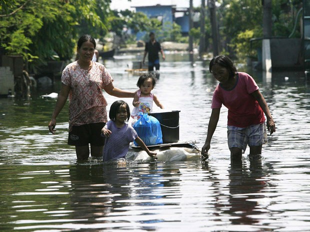 Moradores circulam por rua alagada nas Filipinas (Foto: AFP)