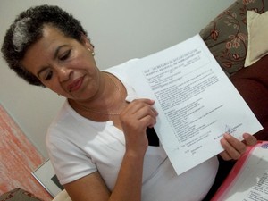 A professora Maria Aparecida Nere exibe o documento atestando a presença de um tumor na mama esquerda (Foto: Lucas Nanini/G1)