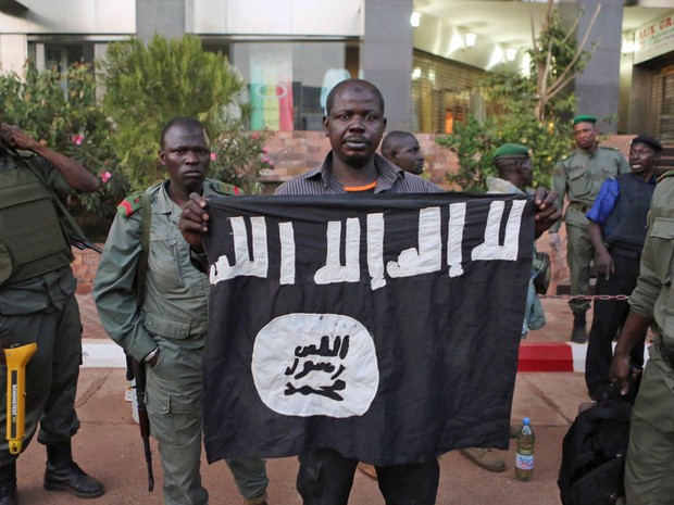 Policiais exibem bandeira que dizem ser de terroristas que invadiram hotel no Mali (Foto: Joe Penney/Reuters)