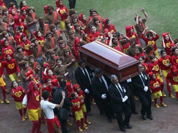 Seguido por dezenas de crianças vestidas de Chaves e Chapolin, o caixão de Roberto Gómez Bolaños é carregado durante cerimônia de homenagem ao humorista mexicano no Estádio Azteca na Cidade do México, no domingo (30) (Foto: Marco Ugarte/AP)