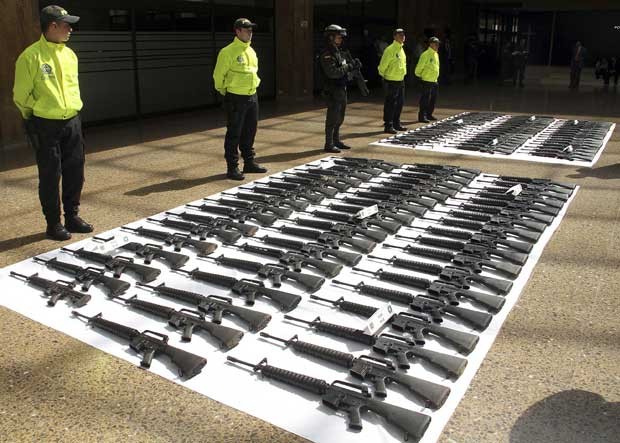 Policiais guardam nesta segunda-feira (23) em Bogotá parte do arsenal que, segundo as autoridades, seria destinado às Farc (Foto: AP)