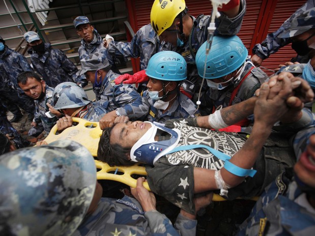 Jovem Pemba Lama é resgatado pelas equipes do Nepal e dos Estados Unidos após ficar soterrado por 5 dias sob os escombros de prédio que desabou durante terremoto na capital Katmandu (Foto: AP/Niranjan Shresta)