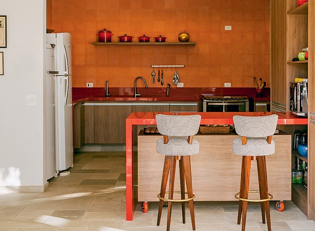 A cozinha do projeto do escritório Arkitito é praticamente monocromática, com ladrilho hidráulico, bancadas e panelas laranjas (Foto: Edu Castello/Casa e Jardim)