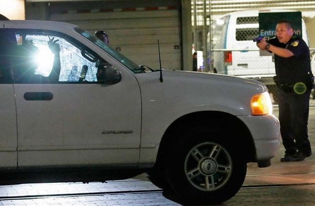 Policial para um motorista no centro de Dallas, após ‘snipers’ balearem agentes durante protesto (Foto: L M Otero / AP Photo)