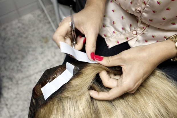 A cabeleireira Adriana da Silva cola as fitas double face na borda da prótese capilar (Foto: Marcos Ferreira/ Ag. Brazil News)