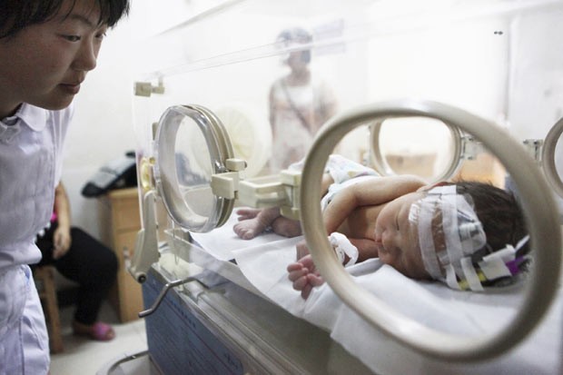 Enfermeira observa nesta terça-feira (28) em hospital de Jinhua o bebê abandonado que foi resgatado de cano de esgoto na China (Foto: China Daily/Reuters)