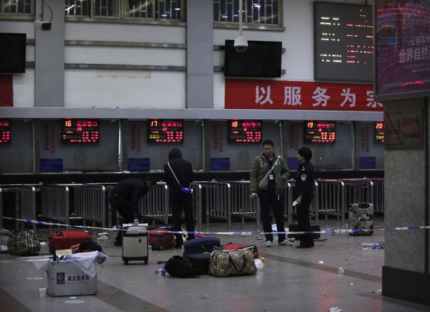 Policiais observam bagagem de passageiros em estao de trem alvo de ataque na China (Foto: Reuters)