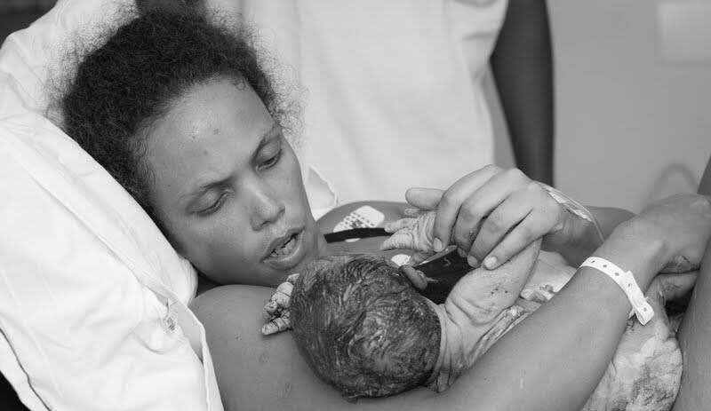 Morgana Eneile segura o filho Teodoro nos braços. Para aliviar o desconforto durante o parto, ela teve a ajuda física e emocional de uma doula (Foto: Amanda Alexandre Fotografia)