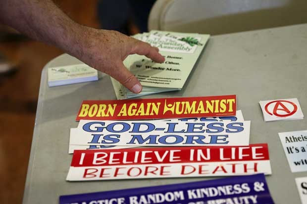Participante pega folhetos e adesivos da "nova religião" durante a primeira celebração dominical em Los Angeles, nos EUA (Foto: Jae C. Hong/ AP)