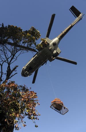 Helicóptero da Força Aérea da Indonésia transporta neste sábado (11) corpos de vítimas de acidente aéreo (Foto: AP)