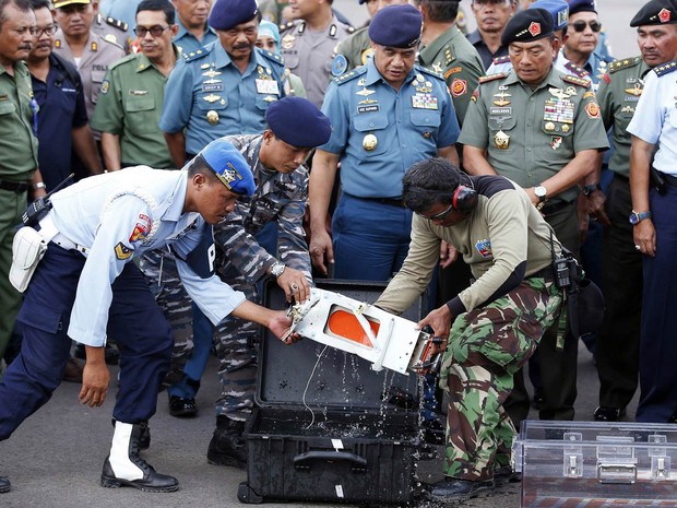 Caixa-preta do voo da AirAsia QZ8501 é transferida para um compartimento transparente após chegar à base aérea de Pangkalan Bun, na Indonésia. O equipamento foi encontrado por mergulhadores e deve ajudar a esclarecer o acidente aéreo (Foto: Darren Whiteside/Reuters)