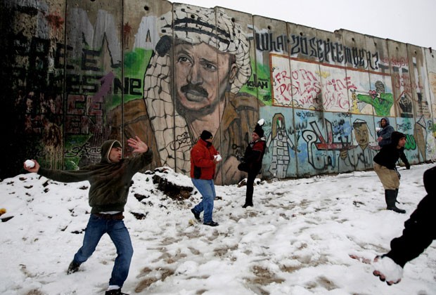 Palestinos brincam com bolas de neve na fronteira entre Jerusalém e a cidade de Ramallah nesta quinta-feira (10)  (Foto: Majdi Mohammed/AP)