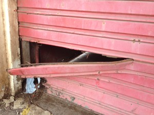 Buraco no portão do galpão serviu para o furto ser realizado (Foto: Abinoan Santiago/G1)