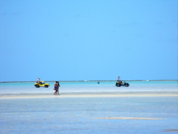 Banhistas dividem espaço com veículosem banco de areia que antecede o mar (Foto: Waldson Costa/G1)