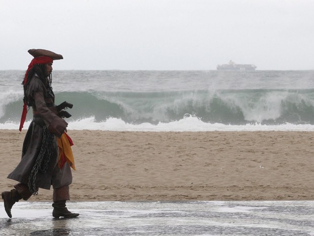 Com a paisagem cinzenta ao fundo, homem vestido de "Jack Sparrow" , personagem do ator Johnny Depp no filme Piratas do Caribe, caminha no calçadão da Praia de Copacabana. (Foto: Márcio Alves / Agência O Globo)