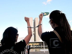 Agentes levantam os braços com algemas, em frente ao Congresso Nacional (Foto: Lucas Nanini/G1)