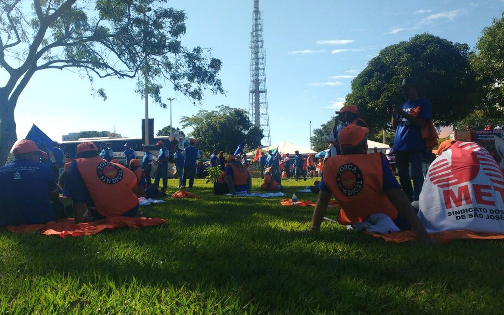 Manifestantes descansam em gramado em frente à Torre de TV em Brasília antes de ato contra reformas do governo Temer (Foto: Elielton Lopes/G1)