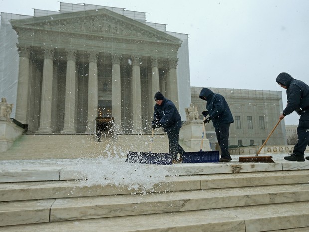 rabalhadores usam pás e vassouras para remover uma mistura pesada de neve e gelo em frente à Suprema Corte dos EUA (Foto: Chip Somodevilla / Getty Images / AFP)