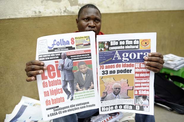 Vendedor em Luanda, capital de Angola, mostra neste sábado (1º) jornais com notícias sobre a eleição da véspera no país (Foto: AFP)