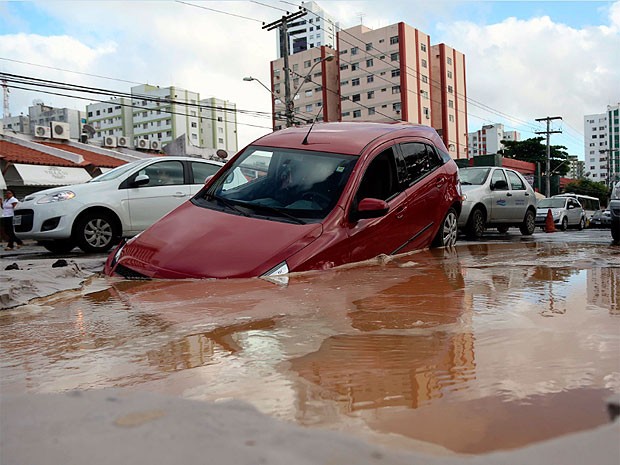 Carro 'afunda' em buraco no  bairro do Imbuí, em Salvador (Foto: VANER CASAES/BAPRESS/ESTADÃO CONTEÚDO)