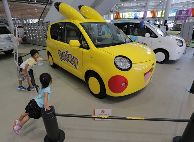Crianças olha carro Porte, da Toyota, decorado com motivo da série de anime Pokémon em showroom da marca em Tóqui nesta sexta-feira (3) (Foto: Itsuo Inouye/AP)