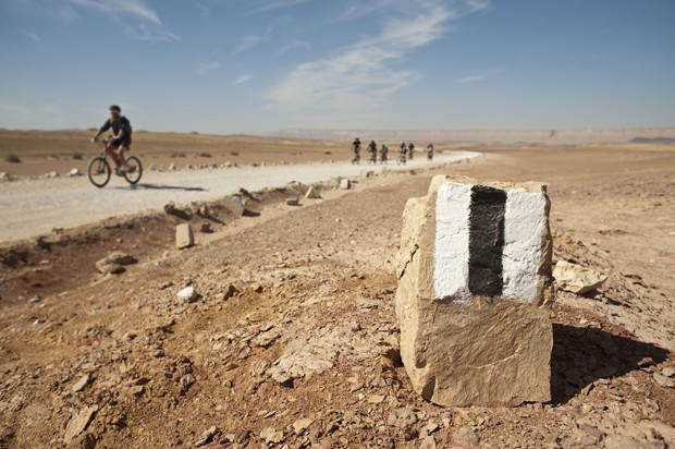 Desert trail marker in the desert with mountain bikers blurred in the background. (Foto: Getty Images/iStockphoto)