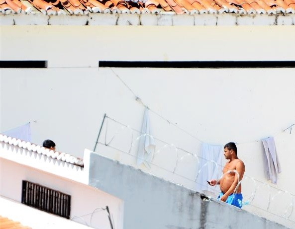 Segundo a direção de Alcaçuz, fotos que mostram preso fazendo uso de um aparelho celular foram feitas do alto de uma das guaritas da unidade (Foto: Divulgação/Tribuna do Norte)