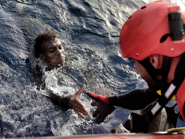 Migrante é resgatado do Mar Mediterrâneo nesta segunda-feira (3) por membro da ONG Proactiva Open Arms (Foto: ARIS MESSINIS / AFP)